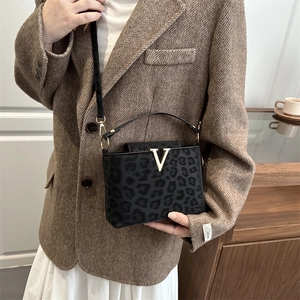 Chic leopard print crossbody handbag with gold V-detail shown in a lifestyle setting