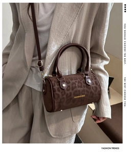 Close-up of leopard print Boston bag featuring gold hardware and cylindrical top handles