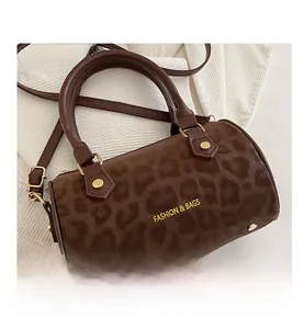 Detail of leopard print cylinder bag with gold rivets and fashion brand lettering