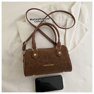 Top view of retro leopard print cylinder bag with gold studs next to a smartphone for scale