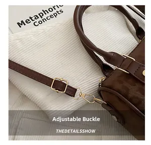 Detail of light gold adjustable buckle and swivel hook on brown suede shoulder bag