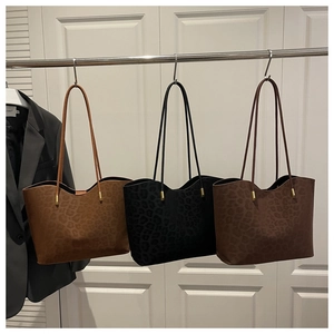 Detailed view of leopard print tote bags in three colors hanging on metallic hooks