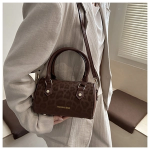Close-up of brown leopard print barrel bag with fashion text and shoulder strap