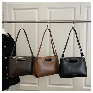 Close-up of three leather handbags in black, brown, and coffee with double strap design