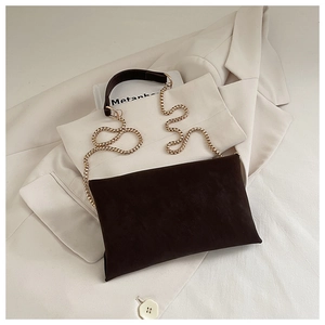 Detail of dark brown suede envelope bag featuring a gold bead chain and leather handle