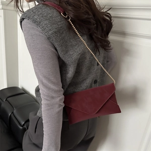 Minimalist burgundy envelope crossbody bag with gold chain strap in premium matte leather