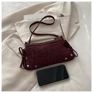 Détail du sac bandoulière rouge foncé à motif léopard avec nœuds latéraux et rivets
