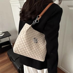 Chic beige tote bag with M-letter monogram and silver metal logo on model shoulder