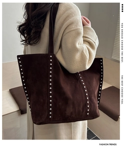 Deep brown suede tote bag with silver rivets shown on shoulder for daily use