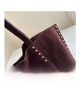 Close-up of brown suede tote bag with stylish silver metal rivets on side and strap