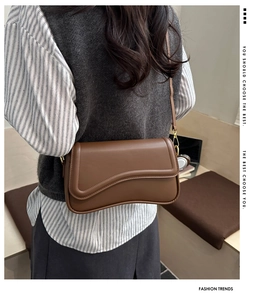 Caramel brown leather crossbody bag with a wave flap design shown on a model
