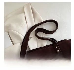 Close-up of dark brown suede tote bag featuring metallic stud details on the side