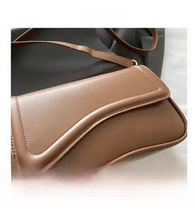 Detail of caramel leather crossbody bag with irregular curved flap and precision stitching