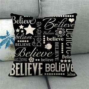 Detail view of linen pillow cover with Believe typography and black stars on a sofa