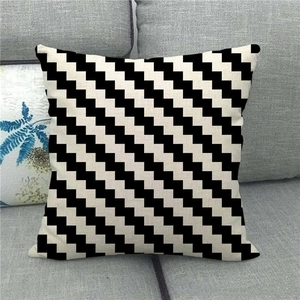 Linen pillow cover with black and white zigzag geometric pattern on a gray sofa