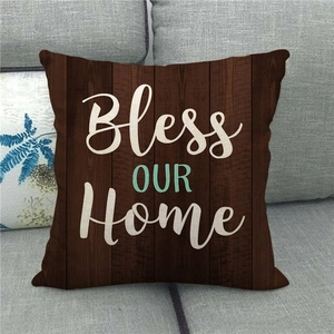 Detail of linen pillowcase with dark wood grain print and Bless Our Home text on a sofa