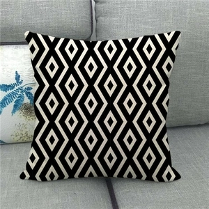 Close-up of geometric linen pillow cover with black and white rhombus patterns on a sofa