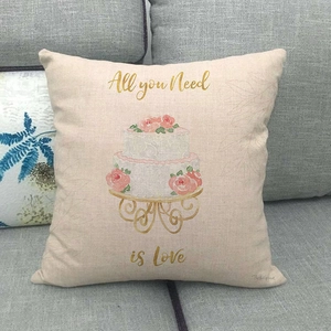 Detail of linen pillowcase with cake illustration and All you Need is Love text on a sofa