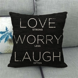 Detail of black linen pillow cover featuring white Love Strong Worry Less text on sofa