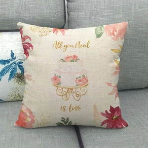 Detailed close-up of linen pillow cover featuring floral cake and All you Need is Love text