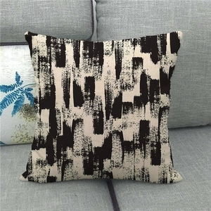 Close-up of linen pillow cover with black abstract brush strokes on grey fabric sofa