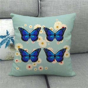 Close-up of linen pillowcase with blue butterfly pattern and white daisy details on sofa