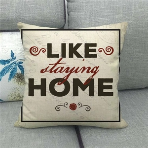 Linen decorative pillow cover with LIKE staying HOME text on a grey fabric sofa