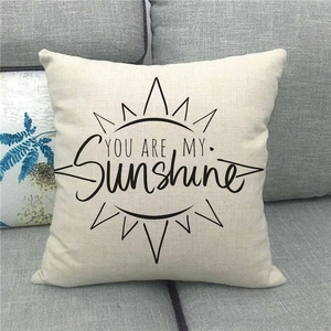 Close-up of linen cushion cover with YOU ARE MY Sunshine text on a grey fabric sofa
