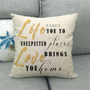 Linen cushion cover with inspirational quote text resting on a modern grey fabric sofa