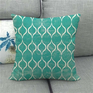 Close-up of cyan linen pillowcase with white geometric patterns on a grey sofa