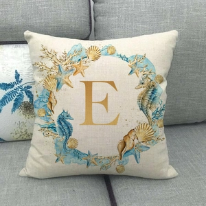Detail of linen pillowcase featuring a golden letter E with blue marine life patterns