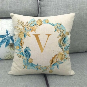Detailed macro of seahorse and starfish wreath around letter V on linen pillowcase