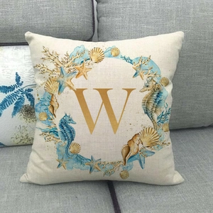 Detailed macro view of linen texture and sea life wreath with gold letter W on cushion