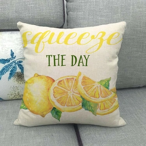 Linen lemon pillow cover with Squeeze The Day text on a modern grey sofa
