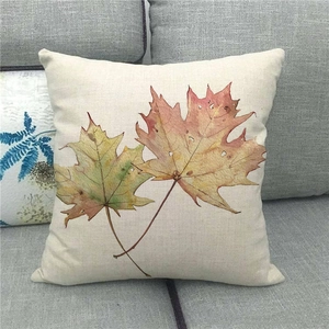 Détail de la housse de coussin en lin avec feuilles d'érable sur canapé gris