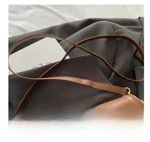 Detail of adjustable leather strap and gold hardware on a brown minimalist handbag