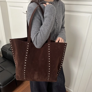 Vintage large brown suede tote bag with silver studs worn by a model in a modern room