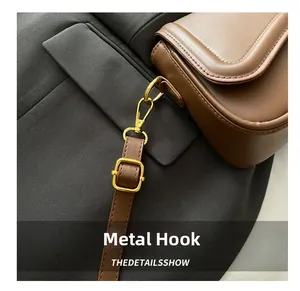 Close-up of golden metal hook and adjustable brown leather strap on a small crossbody bag