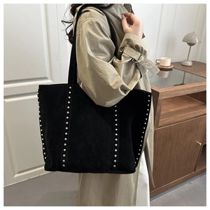 Detail of black suede tote bag featuring silver rivet studs and long shoulder straps