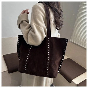 Detail of silver rivets on dark brown suede tote bag with elegant vintage texture