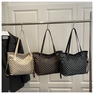 Three Jacquard tote bags in beige, brown, and black hanging on a metal display rack