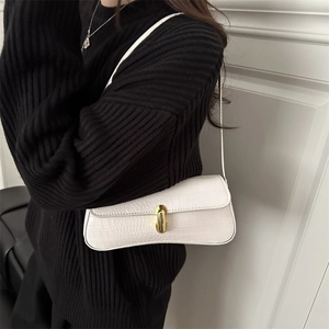 Sac baguette blanc à motif crocodile et boucle dorée porté par un mannequin