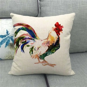 Detailed watercolor rooster print on a square linen pillowcase atop a grey fabric sofa