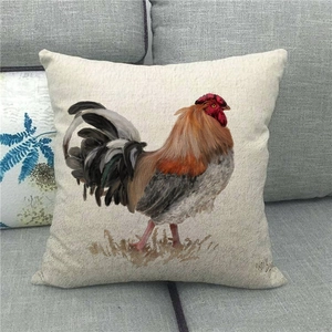 Detail of linen cushion cover featuring watercolor rooster art on grey sofa