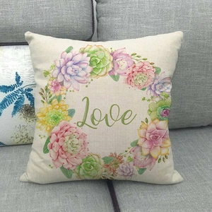 Fodera per cuscino in lino con ghirlanda floreale e scritta Love su divano grigio