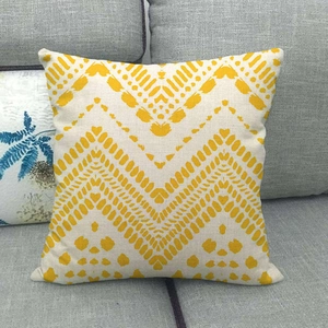 Housse de coussin en lin minimaliste avec motifs zigzag jaunes sur un canapé gris