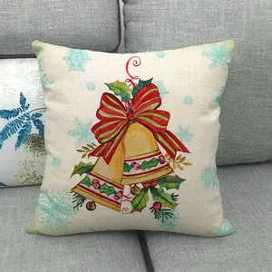 Christmas linen pillowcase with golden bells and striped bow on a grey fabric sofa