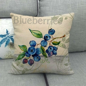 Detail of linen cushion cover with realistic blueberry pattern on a gray sofa