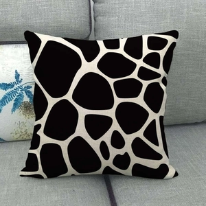 Linen decorative pillow cover with black and beige giraffe pattern on a grey sofa