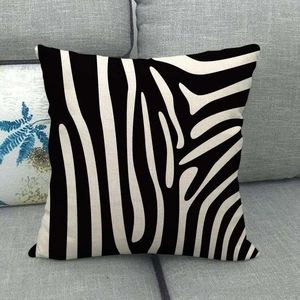 Square linen pillow cover with black and white zebra pattern on a grey sofa